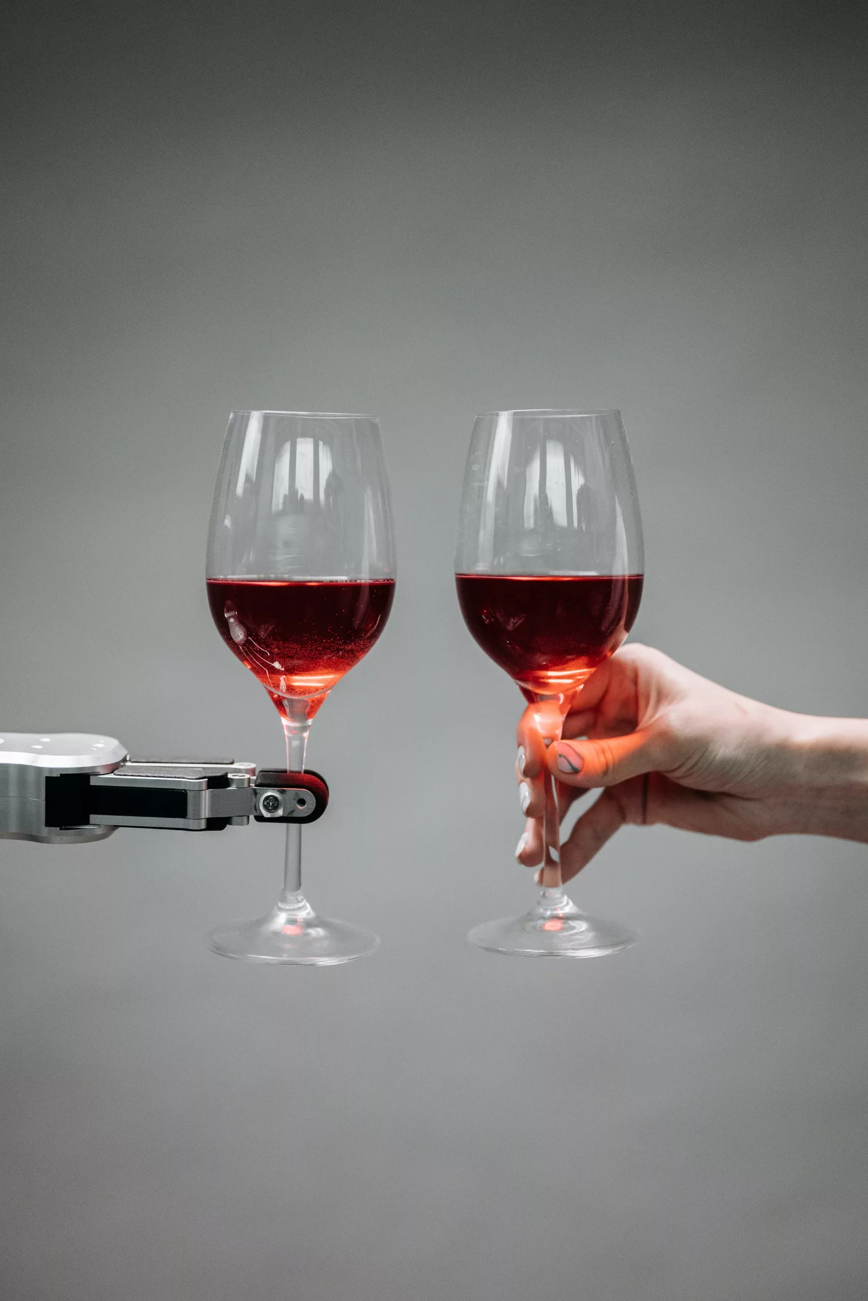 Main robot et humaine qui trinque un verre